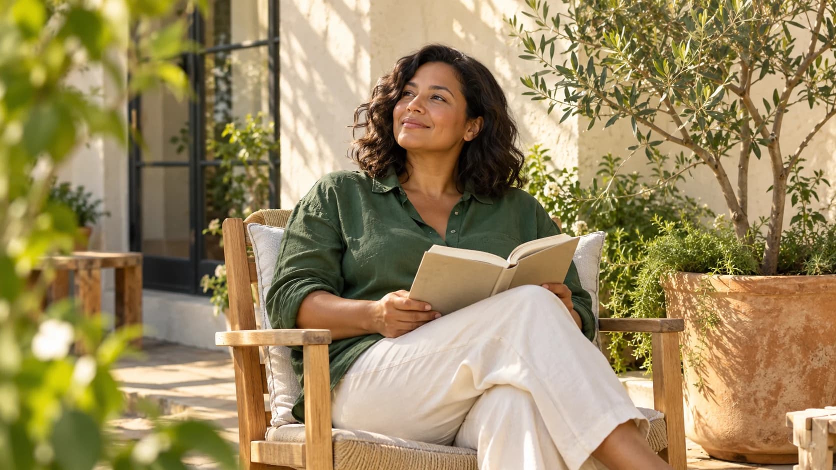 A woman taking a quiet moment to read on a sunlit patio.